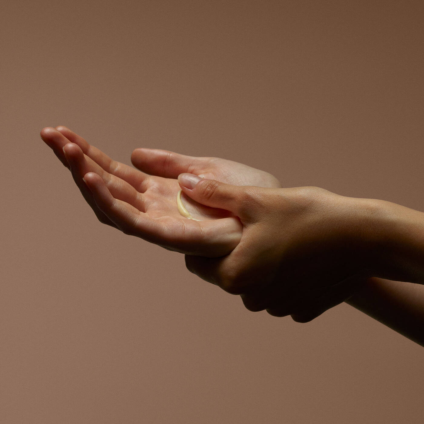 Hands receiving balm in a dim evening ritual